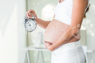 Midsection of woman holding alarm clock