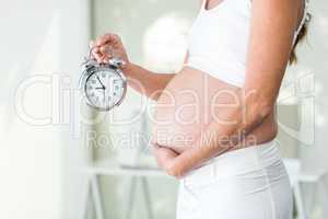 Midsection of woman holding alarm clock