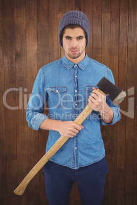 Serious hipster wearing knitted hat holding axe