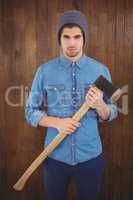 Serious hipster wearing knitted hat holding axe
