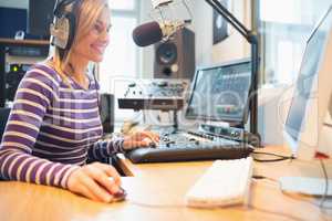 Female radio host using computer while broadcasting