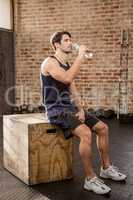 Man sitting on plyo box and drinking water