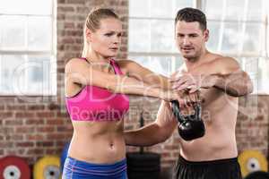 Attentive muscular trainer show how to lift kettlebells
