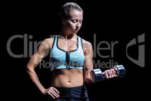 Fit woman exercising by lifting dumbbell