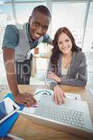 Portrait of smiling business professionals using laptop