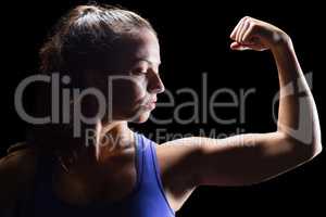 Confident female athlete flexing muscles