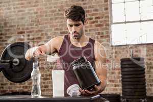 Man adding supplement from tin to bottle