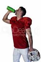Rugby player drinking water and holding helmet