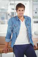 Happy hipster leaning on desk in office