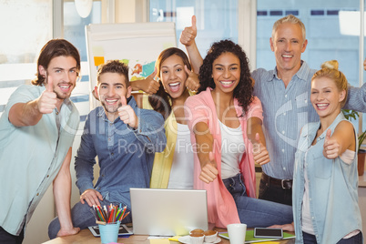 Happy business people with technologies showing thumbs up