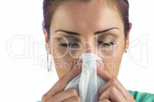 Close-up of woman suffering from blowing nose with tissue on mou