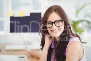 Portrait of smiling woman wearing eyeglasses at desk