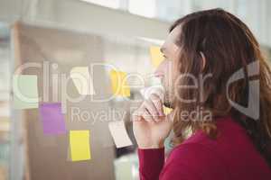 Thoughtful man looking at adhesive notes stuck on glass