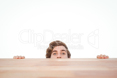 Man hiding behind desk against white background