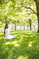 Side view of woman sitting on grassland