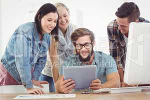 Smiling business people using digital tablet at computer desk