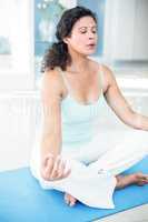 Pregnant woman sitting in lotus pose with eyes closed