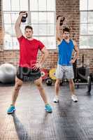 Muscular men lifting kettlebell