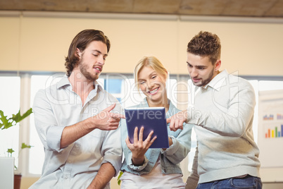 Happy businesswoman holding laptop with colleagues