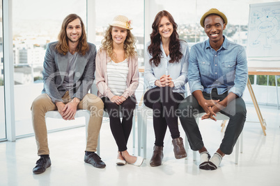 Full length portrait of smiling business people sitting on chair