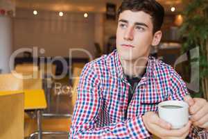 Thoughtful young man holding coffee cup