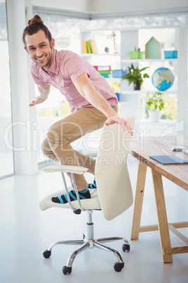 Happy businessman standing on chair in office