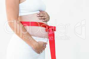 Pregnant woman with a red ribbon around her bump