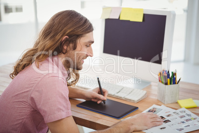 Hipster using graphics tablet while working at desk