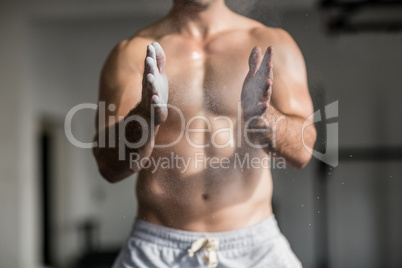 Muscular man shaking chalk off his hands