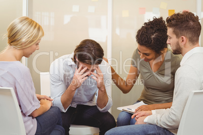 Business people consoling businessman suffering from headache