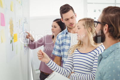 Business people talking while standing at wall with sticky notes