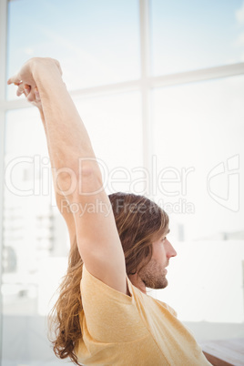 Hipster stretching arms in office