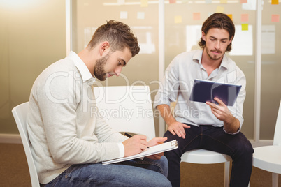 Serious businessmen with digital tablet and document in meeting