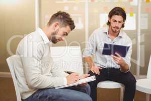Serious businessmen with digital tablet and document in meeting