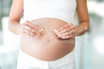 Midsection of woman breaking cigarette against belly