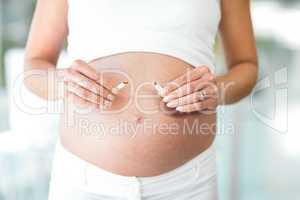 Midsection of woman breaking cigarette against belly