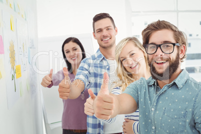 Portrait of smiling business people with thumbs up