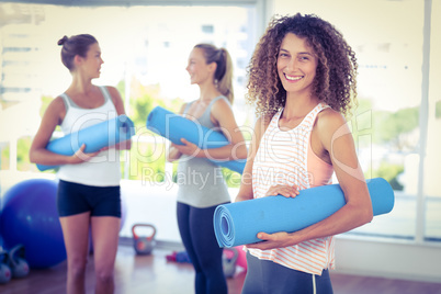 Portrait of woman holding yoga mat and smiling