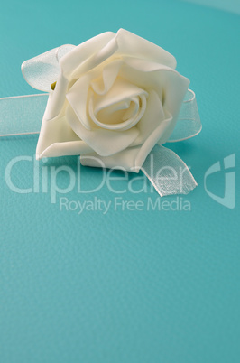 White plastic rose on a turquoise leather background