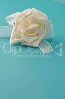 White plastic rose on a turquoise leather background