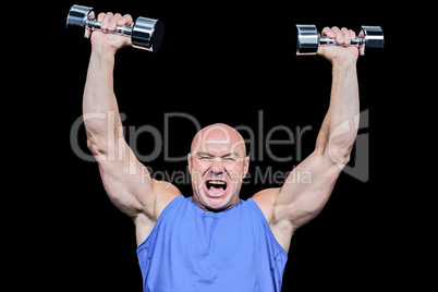 Muscular man with arms raised lifting dumbbells