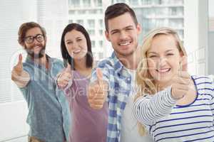 Portrait of smiling business people standing in row with thumbs