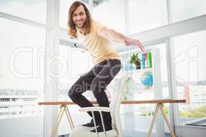 Happy hipster standing on chair in office