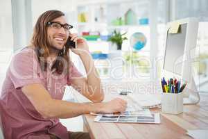 Happy hipster using mobile phone at computer desk