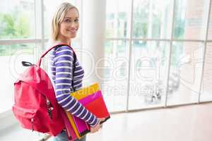 Confident female student with backpack and books