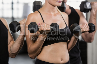 Midsection of people lifting dumbbell