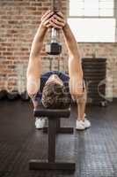 Man lifting dumbbell while lying on bench