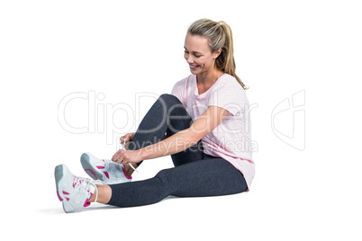 Sporty woman smiling while tying shoelace