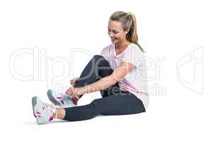 Sporty woman smiling while tying shoelace