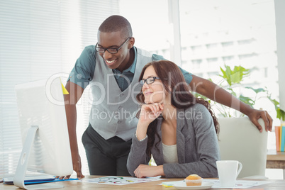 Smiling business professionals looking at computer while working